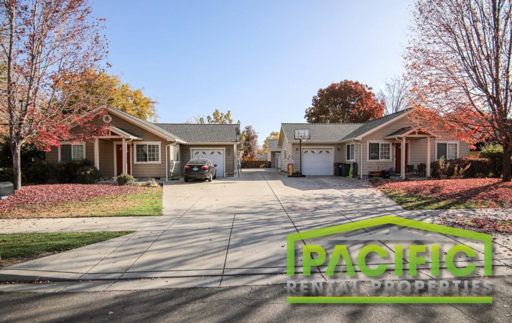 a street with two houses and a car parked in the driveway